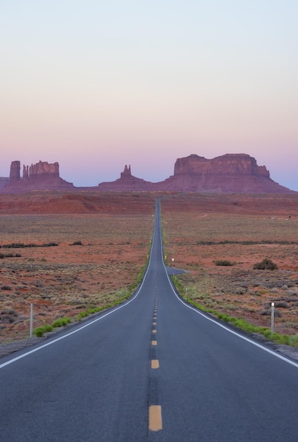 Scenic road in the dry desert with red rocky mountains in background