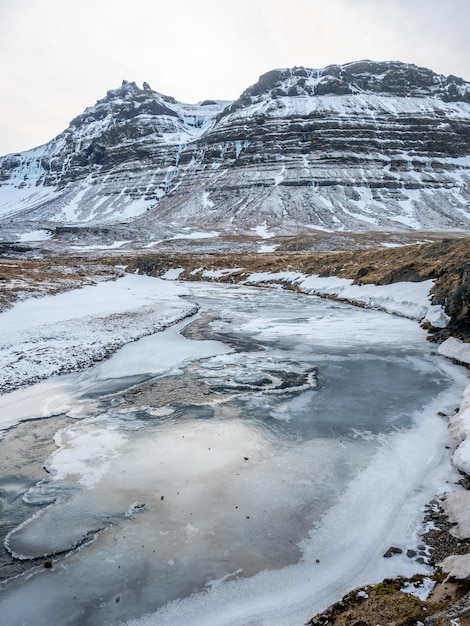 Scenic view around Kirkjufellfoss waterfall in north of Iceland and slippery ice pond