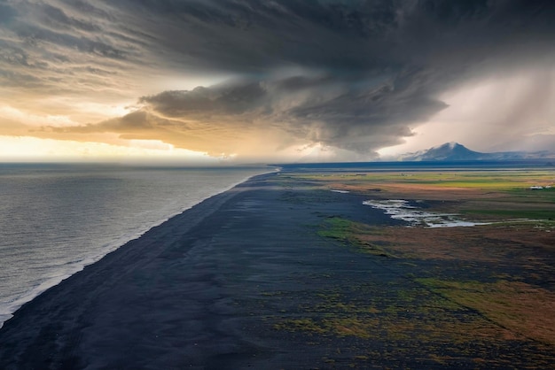 Scenic view of beautiful black sand beach against cloudy sky during sunset