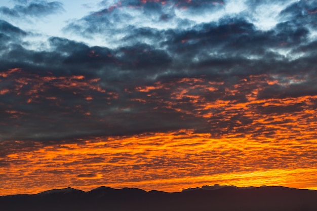 Scenic view of a beautiful sunset with dark sky and colorful clouds over the mountains