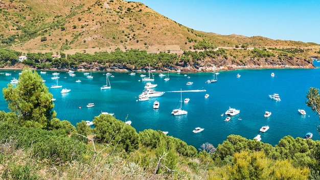 Scenic view at Mediterranean sea Small bay with many white yachts and sailboats in clear blue water Catalonia Spain in summer