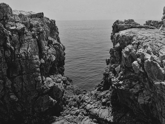 Photo scenic view of rocks by sea against sky