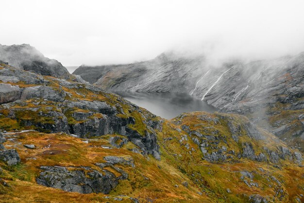 Photo scenic view of rocky mountains and lake against cloudy sky with fog in lofoten norway