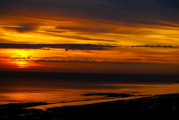 Photo scenic view of sea against dramatic sky during sunset