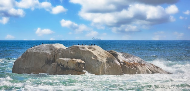 Scenic view of sea rocks and waves in Camps Bay Beach Cape Town South Africa Tidal ocean with shoreline rocks and boulders Overseas travel and tourism destination with blue sky and copy space