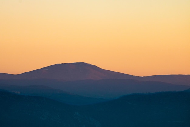 Photo scenic view of silhouette mountains against orange sky