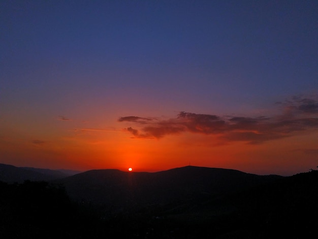 Scenic view of silhouette mountains against orange sky