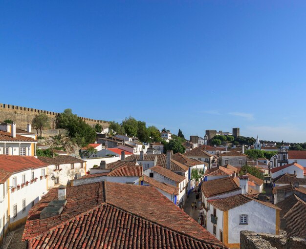 Scenic view of white houses red tiled roofs and castle from wall of fortress Beautiful old town with medieval Obidos village Portugal