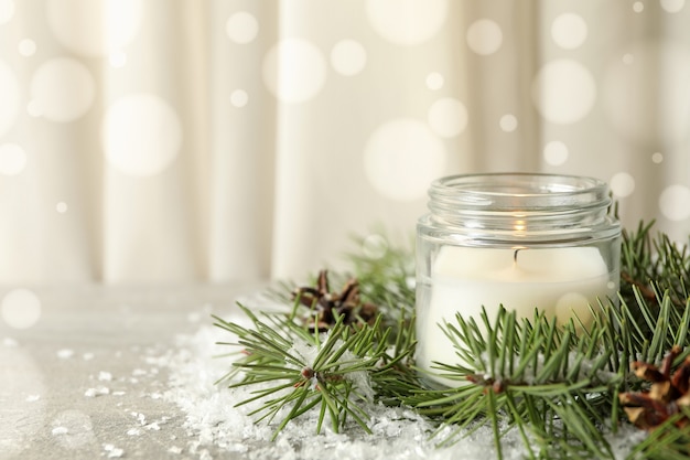 Scented candle, pine branches and snow