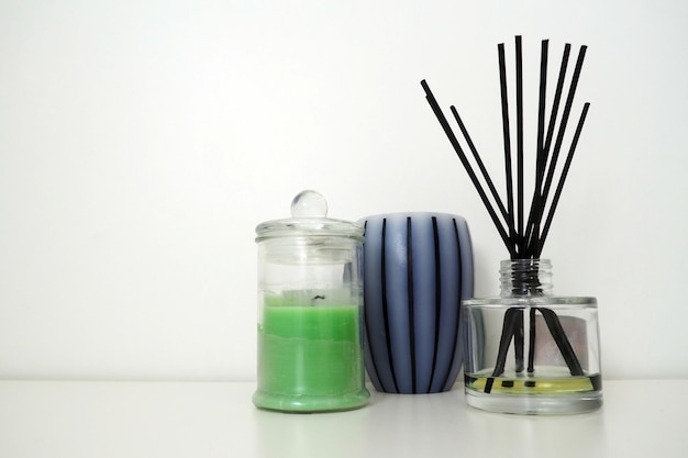 Scented candles on a white background Aromatic sticks soaked in essential oil Glass vessel with oil Still life with decorative items Striped candle wax in a transparent jar with a lid