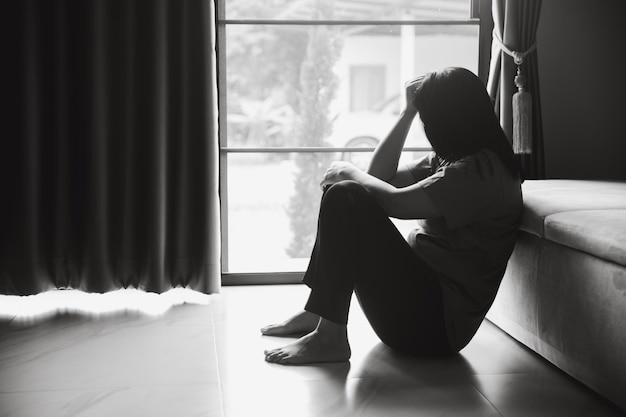 Schizophrenia with lonely and sad in mental health depression concept Depressed woman sitting against floor at home with dark room feeling miserable Women are depressed fearful and unhappy