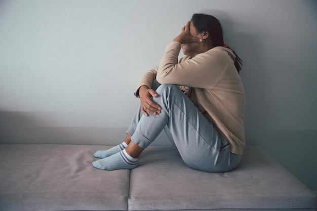 Schizophrenia with lonely and sad in mental health depression concept Depressed woman sitting against floor at home with dark room feeling miserable Women are depressed fearful and unhappy