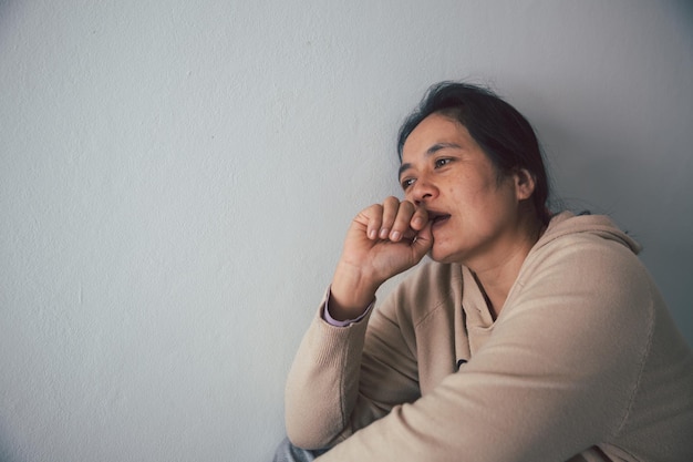 Schizophrenia with lonely and sad in mental health depression concept Depressed woman sitting against floor at home with dark room feeling miserable Women are depressed fearful and unhappy