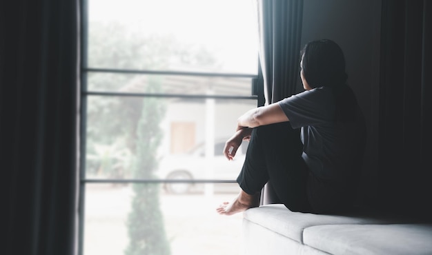 Schizophrenia with lonely and sad in mental health depression concept Depressed woman sitting against on the sofa at home with dark room feeling miserable Women are depressed fearful and unhappy