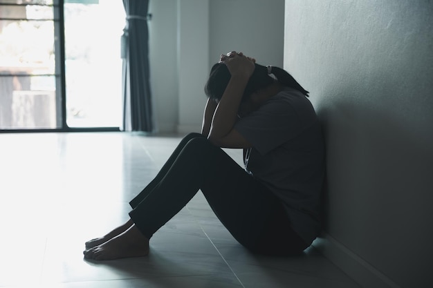 Schizophrenia with lonely and sad in mental health depression concept Depressed woman sitting against wall at home with a shadow on wall feeling miserable Women are depressed fearful and unhappy