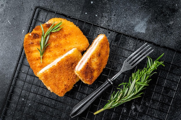 Schnitzel Cordon bleu fillet cutlet with ham and cheese Black background Top view