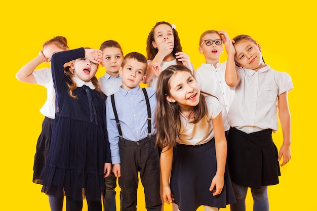 Schoochildren with backpacks and crossed hands standing over yellow background