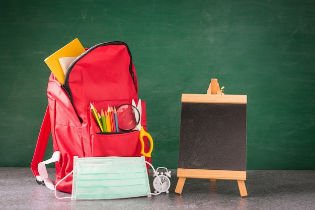 School backpack and accessories with face mask protect at chalkboard