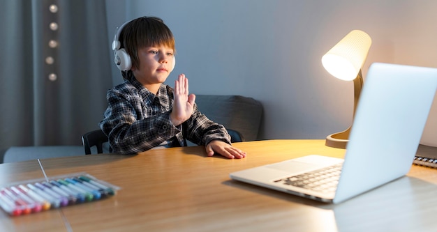 School boy taking online courses and waving