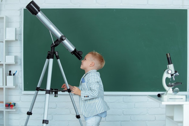 School boy with telescope learning astronomy lesson at school