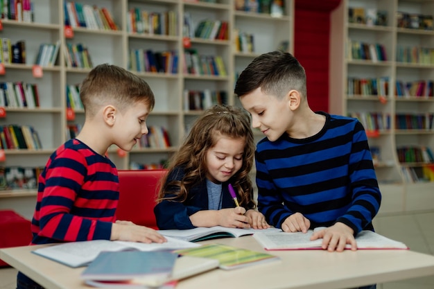 School children in the library reading books, doing homework, prepare a school project for lessons