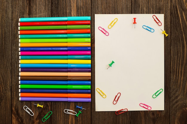 School creative flatley. On a wooden table are multi-colored felt-tip pens and a sheet with empty space for text.