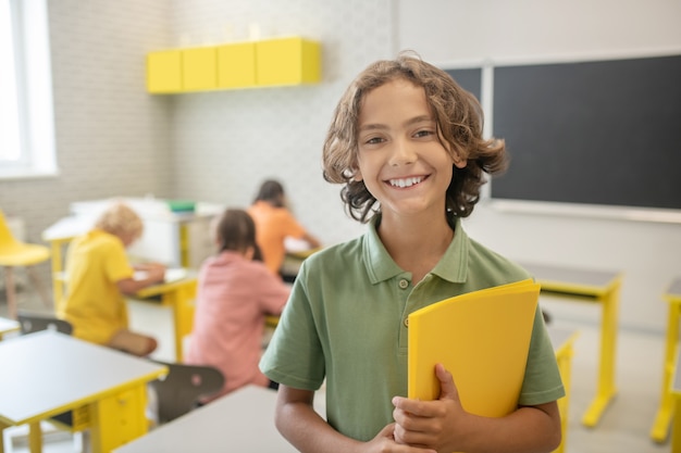 At school. Cute schoolboy in green tshirt smiling nicely