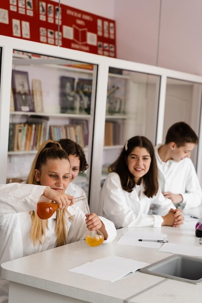 School education Cheerful classmates in chemistry lesson hold flasks with liquid for experiments Happy friends study together in class in laboratory