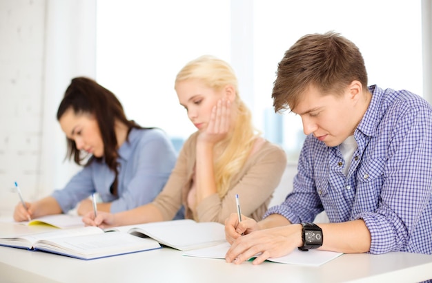 school and education concept - group of tired students with notebooks at school