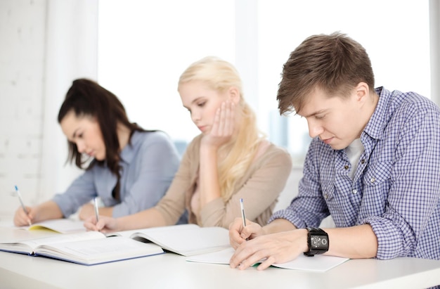 school and education concept - group of tired students with notebooks at school