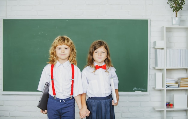 School friends two school kids girl and boy holding hands going at school class in first class