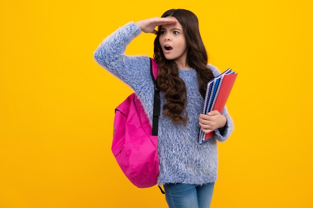 School girl hold copybook and book on yellow isolated studio background School and education concept Teenager girl in school uniform Shocked amazed face surprised emotions of young teenager girl