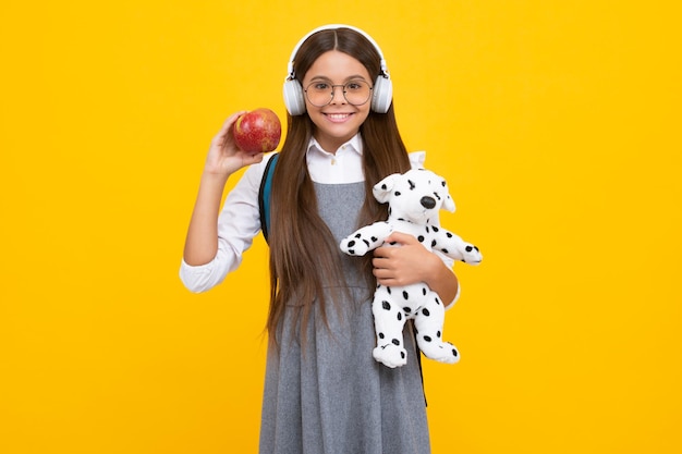 School girl hold toy School children with favorite toys on yellow isolated background Childhood concept Happy school girl positive and smiling emotions