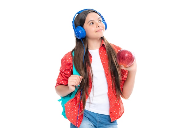 School girl teenage 12 13 14 years old in headphones and books on isolated studio background School kids with backpack