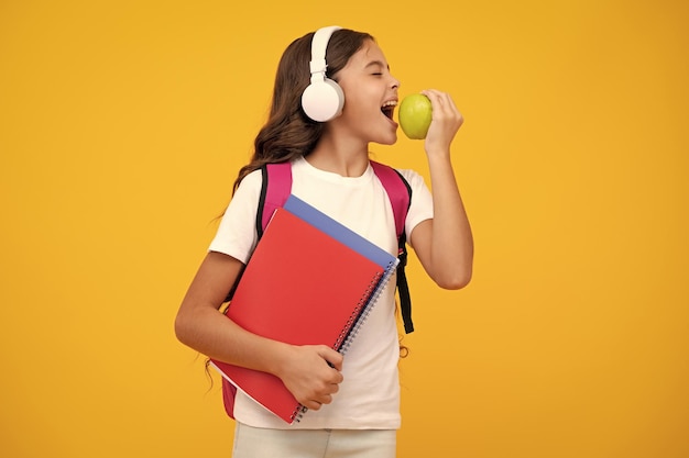 School girl teenage student in headphones and books on isolated studio background School kids