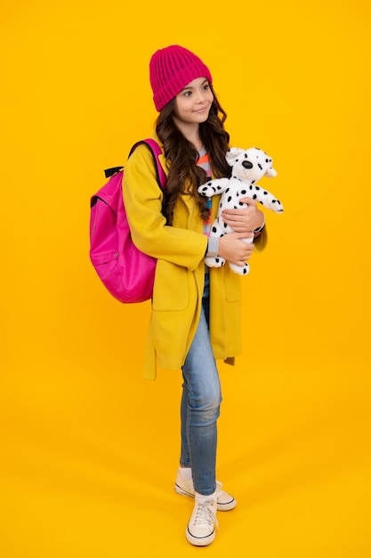 School girl in winter hat hold toy School children with favorite toys on yellow isolated background