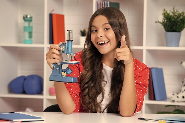 School girl with microscope for school education at home Happy schoolgirl face positive and smiling emotions