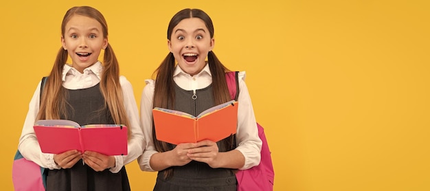 School girls friends Surprised children in formal uniforms read school books yellow background