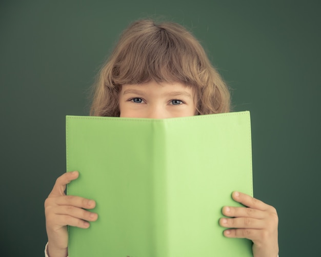 School kid in class. Happy child against green blackboard. Education concept