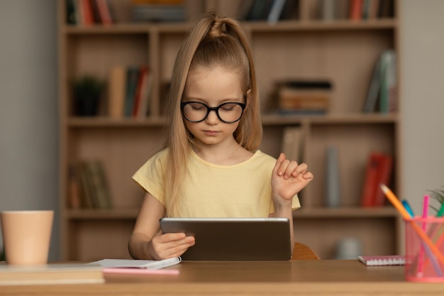 School Kid Girl Using Digital Tablet Doing Homework At Home