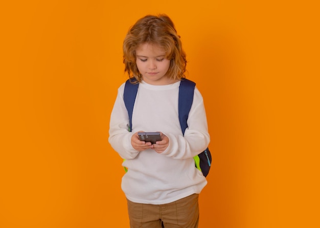 School kid using phone isolated on yellow isolated studio background