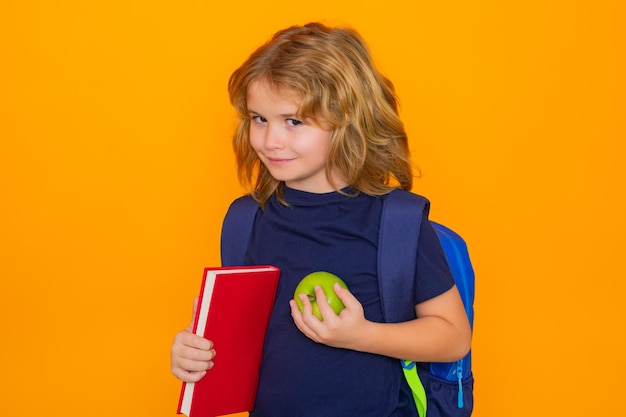 Photo school kids school boy with book isolated on yellow studio background funny little boy from