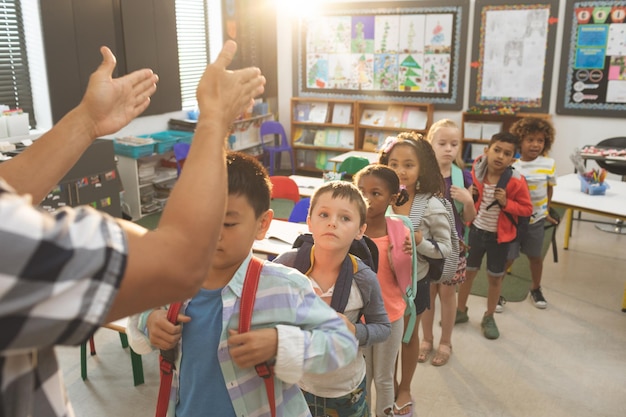 School kids standing and forming a queue in classroom at school