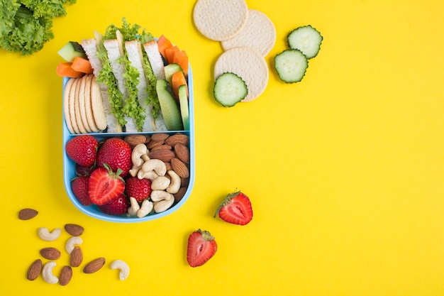 School lunch in the blue box on the yellow background Top viewCopy space