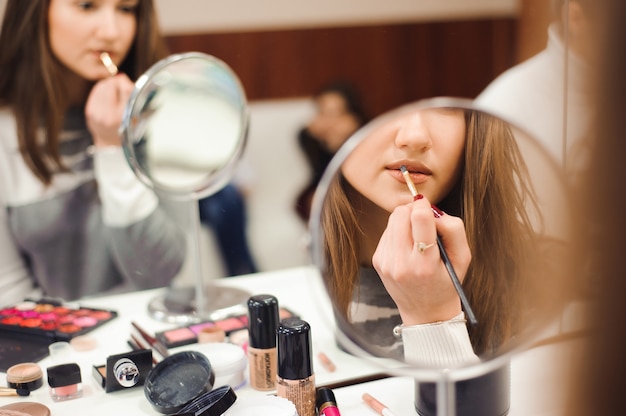 School of makeup. Make up artist doing professional make up of young woman.