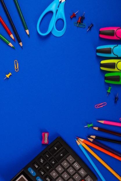 School or office stationery on blue background. Back to School. Frame, copy space. supplies 