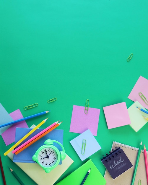 School supplies and an alarm clock on a green background Back to school concept