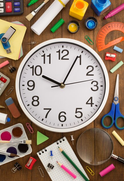 Photo school supplies and clock on wooden table