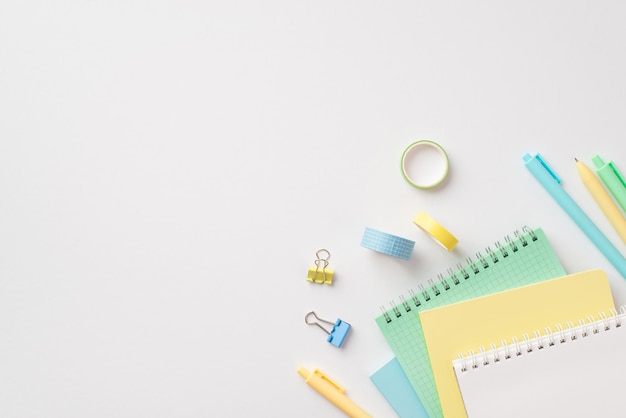 School supplies concept Top view photo of stationery stack of notepads pens binder clips and adhesive tape on isolated white background with copyspace