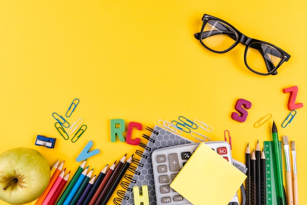 School supplies and eyeglasses on yellow